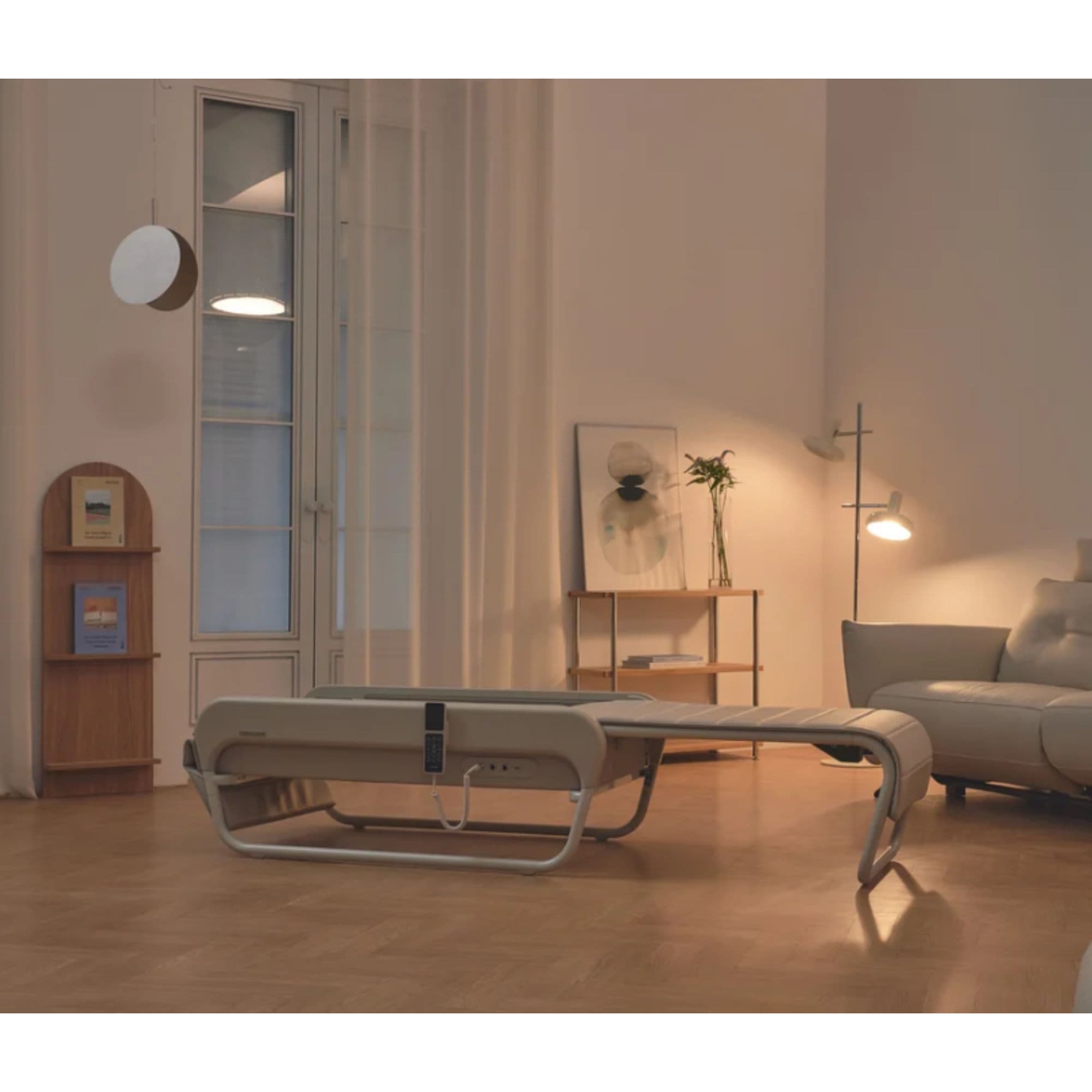 Ceragem Master V5 Massage Bed White Variant Front View With Sofa And Lampshade In Warm Living Space