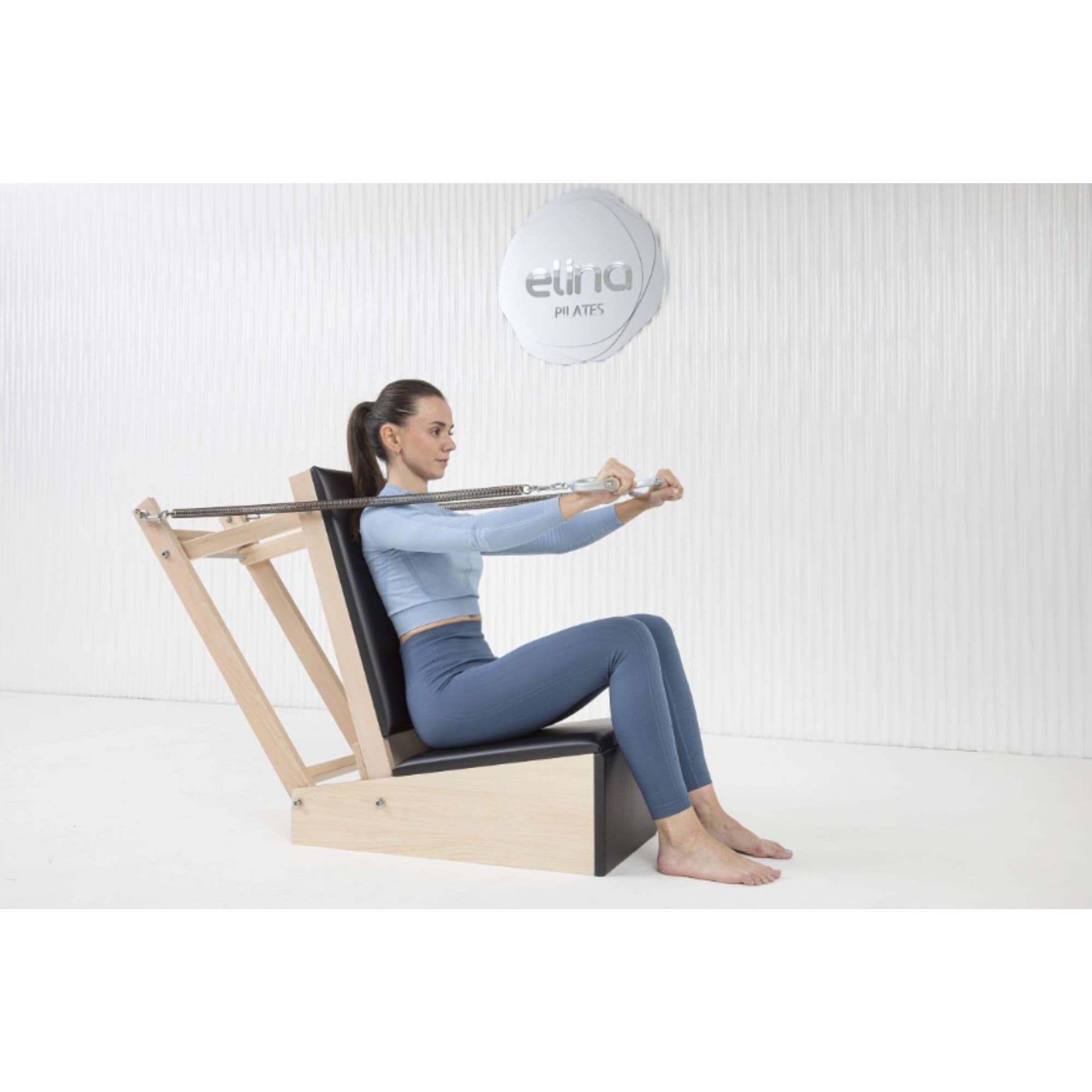Elina Baby Chair With A Woman Performing A Seated Upper Body Pilates Exercise