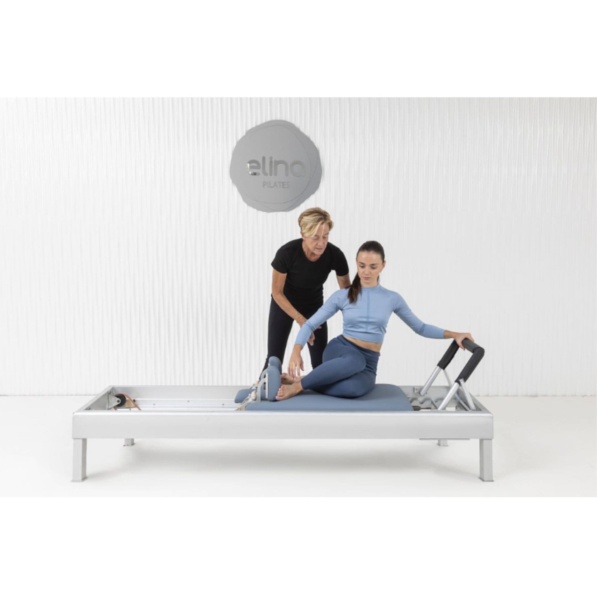 Elina Pilates Classic Aluminium Reformer 86 Inches With One Older Woman Assisting The Young Girl While Performing The Exercise