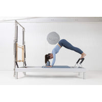 Thumbnail for Elina Pilates Classic Aluminum Reformer & Tower Inches With A Woman Performing Exercise Using The Footbar