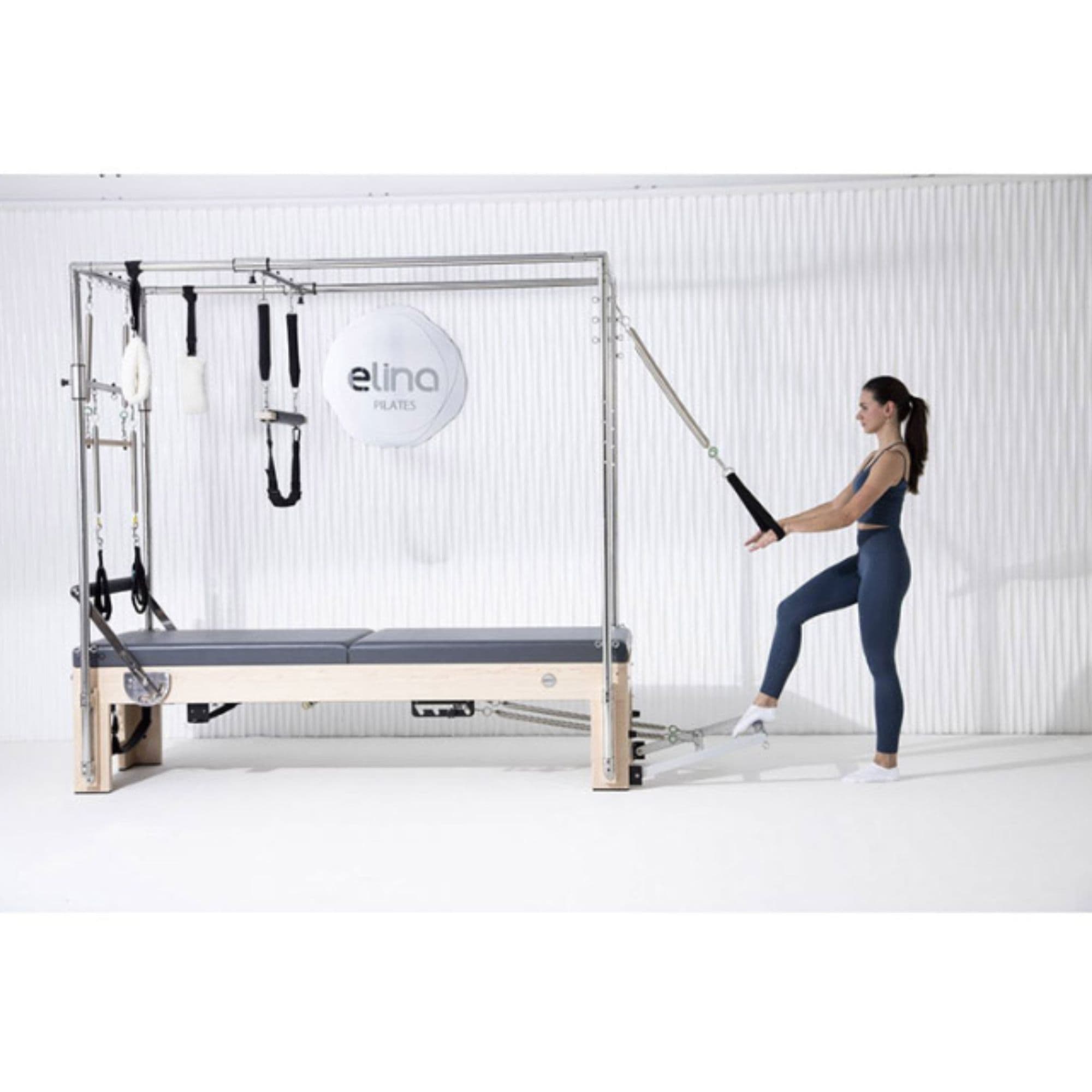 Elina Pilates Elite Cadillac Reformer Machine Grey Variant Side View With A Woman Demonstrating The Exercise