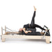 Elina Pilates Elite Wood Reformer Bundle Black Variant With A Woman Lying Down While Raising Her Right Leg