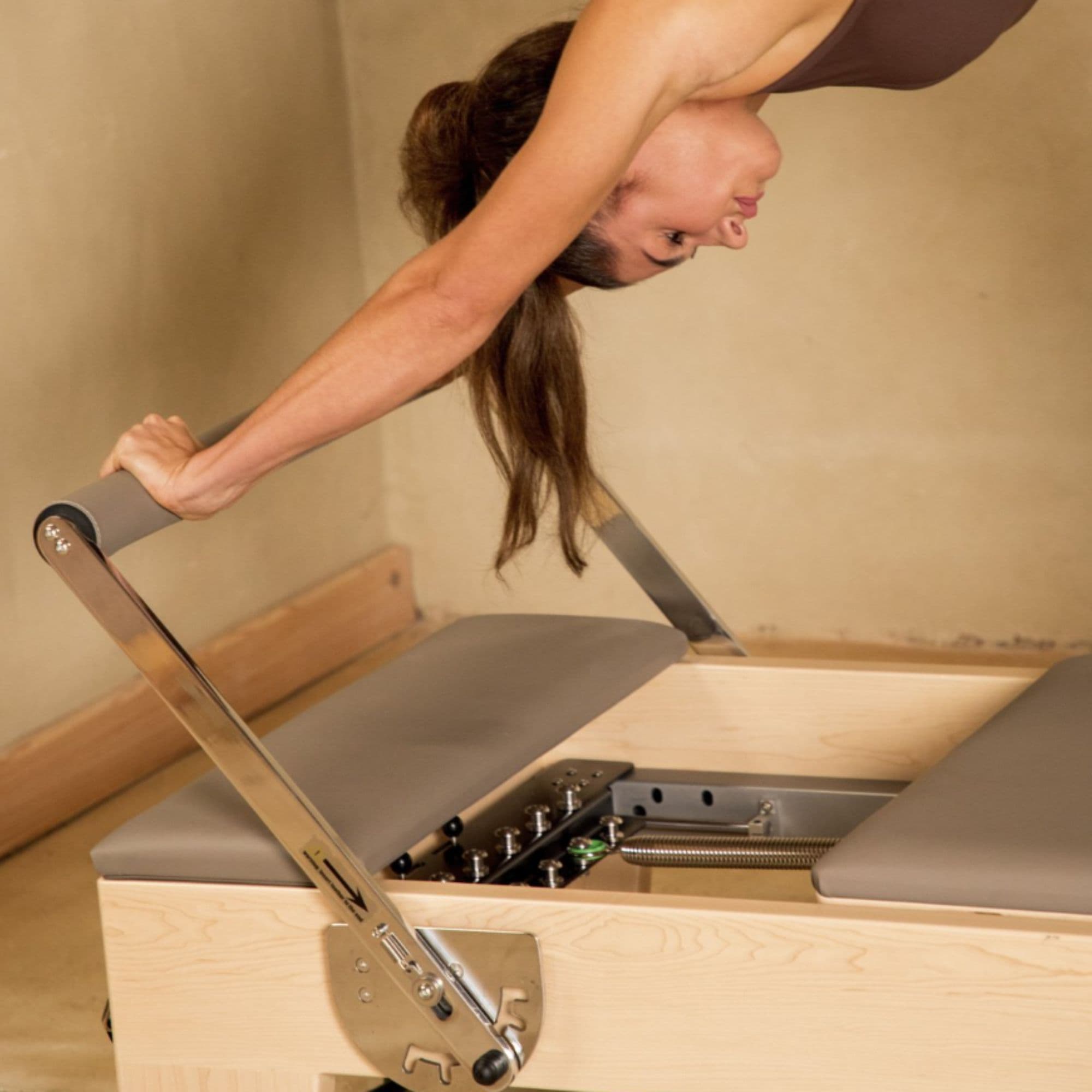 Elina Pilates Elite Wood Reformer Gray Variant With Woman Performing A Stretch Exercise