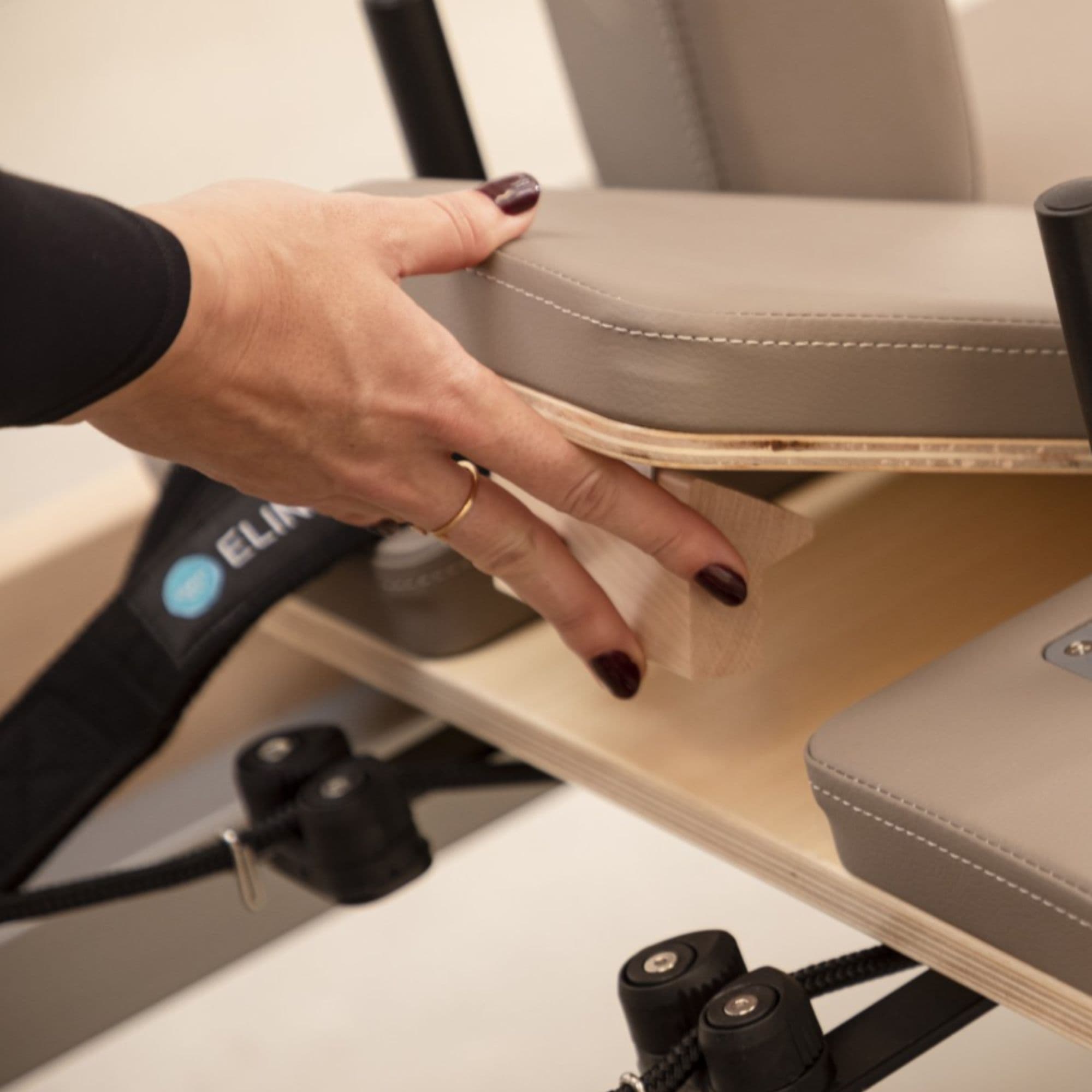 Elina Pilates Master Instructor Wood Reformer Close-Up View Of Hand Adjusting The Removable Seat Support Block