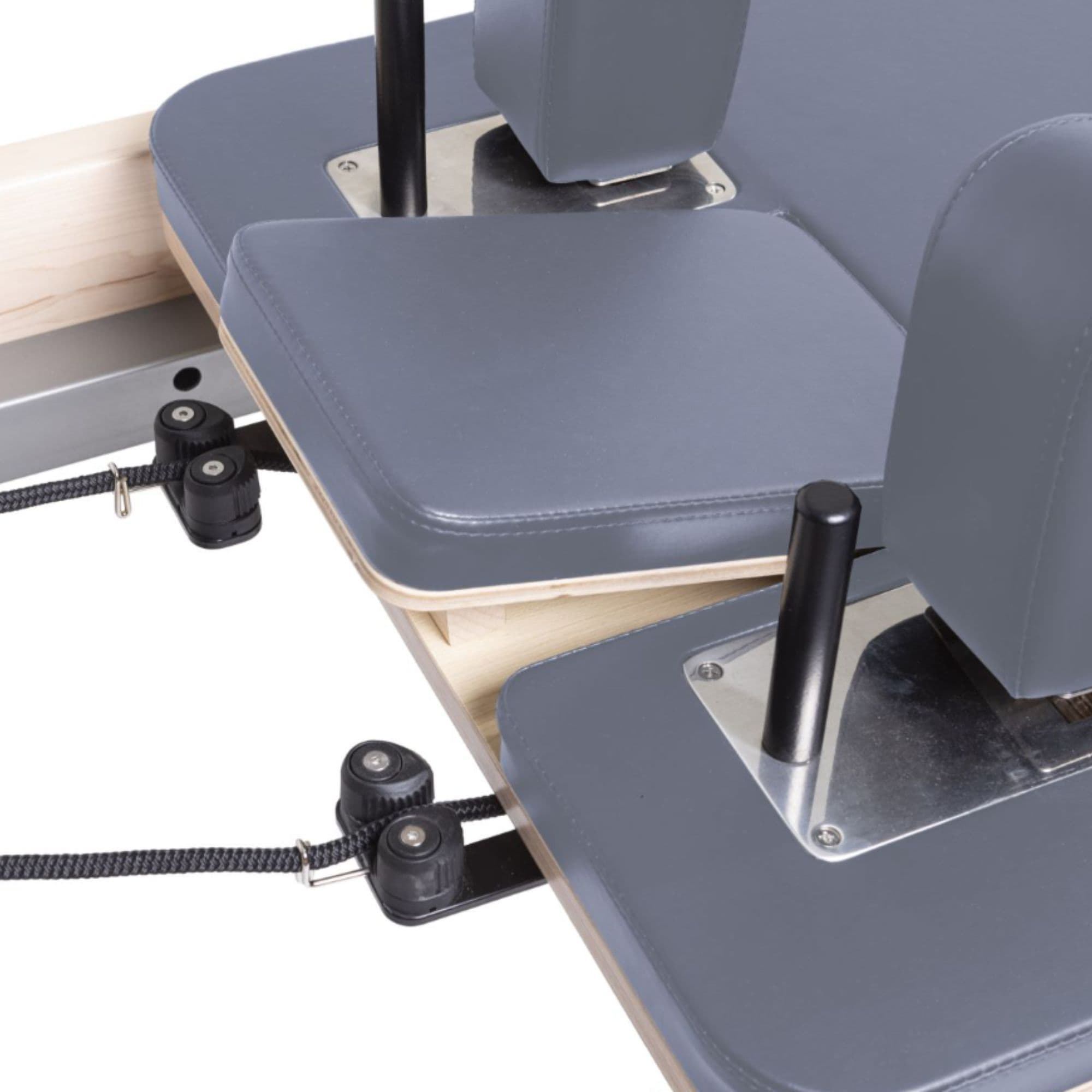 Elina Pilates Physio Reformer Master Instructor Close-Up View Of Reformer Rope Guide Pulleys On Grey Upholstered Bed