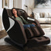 Kyota Joubu M880 4D Zero Gravity Massage Chair Black-Dark Brown Variant Front Angled View Of A Woman Relaxing In A Modern Living Room