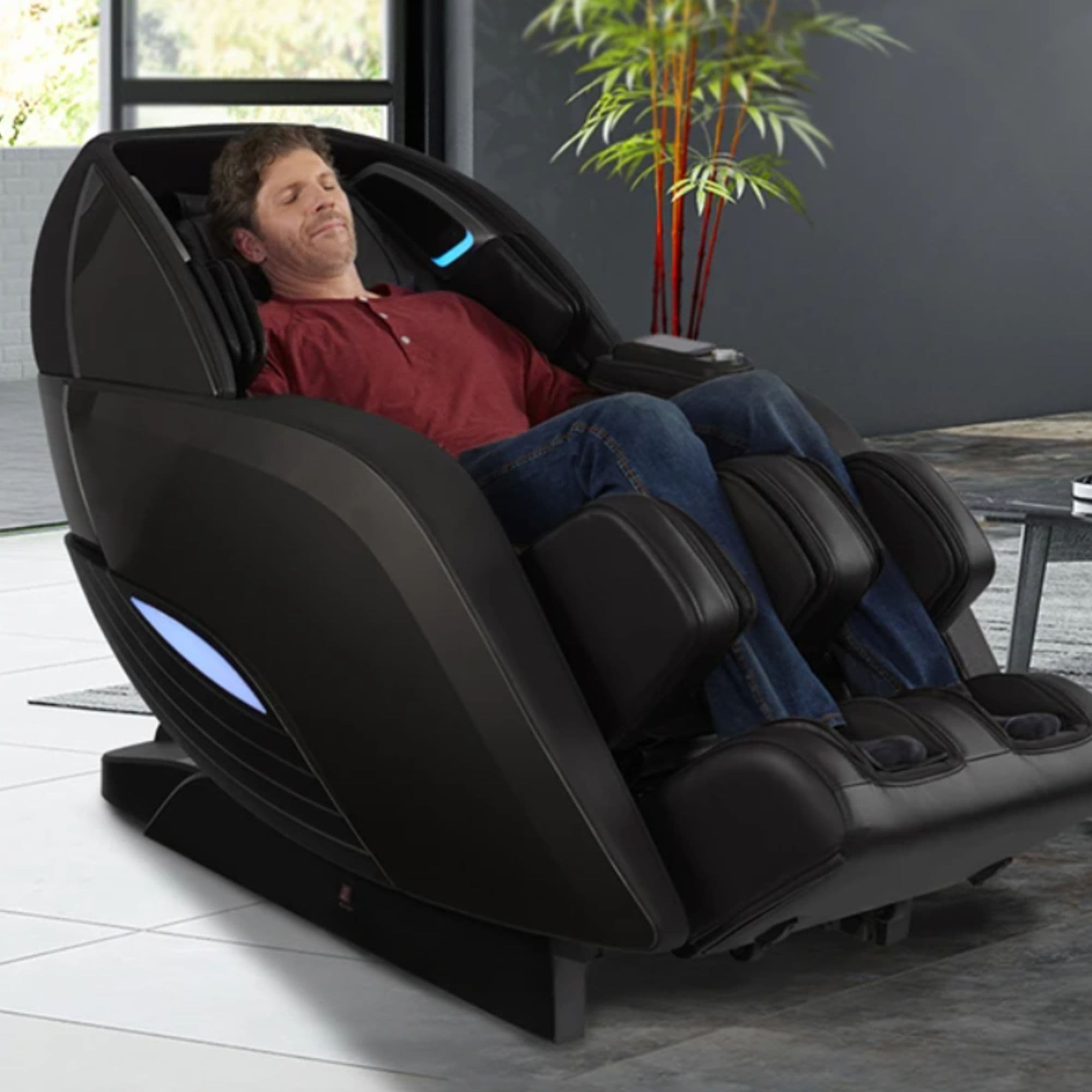 Kyota Yutaka M898 4D Chair Black Variant Front Angled View Of A Man Relaxing In A Modern Living Room With bamboo In The Background