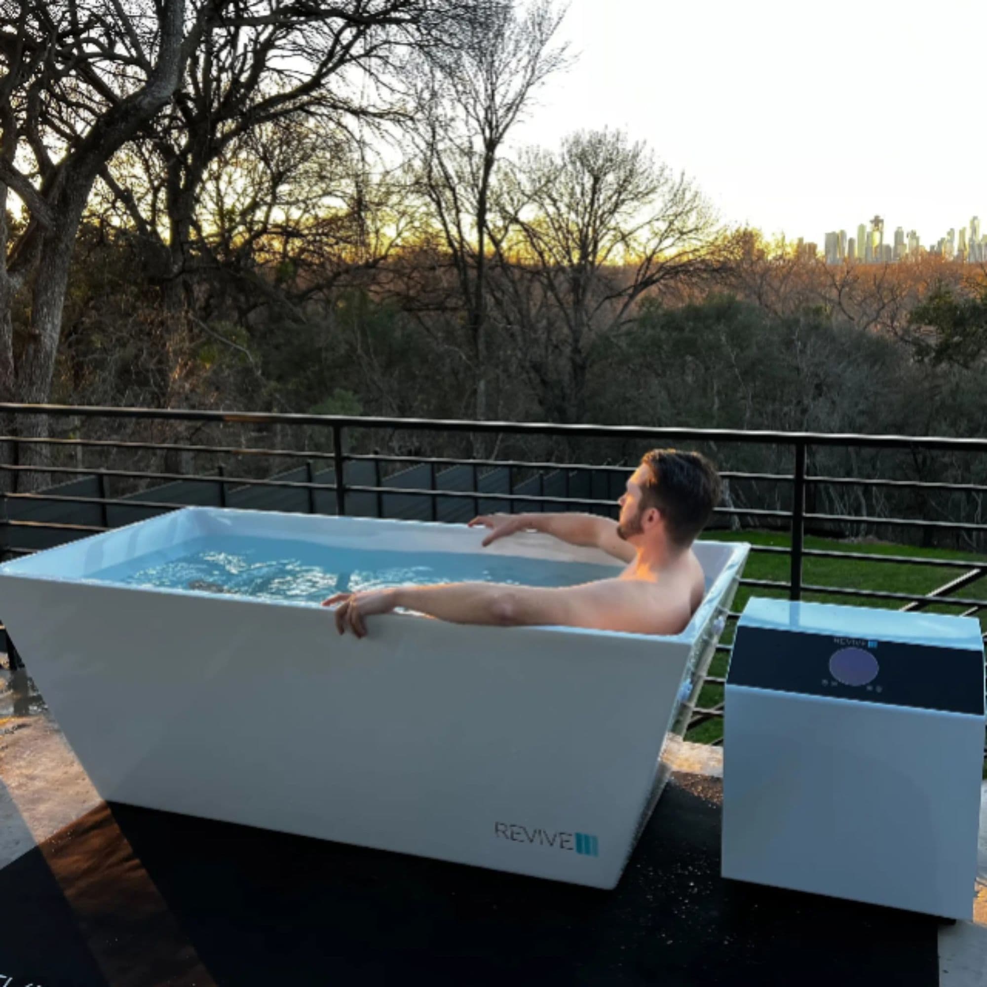 Revive Acrylic All-Weather Cold Plunge Side View With Man Enjoying Cold Water Immersion In Balcony Setting