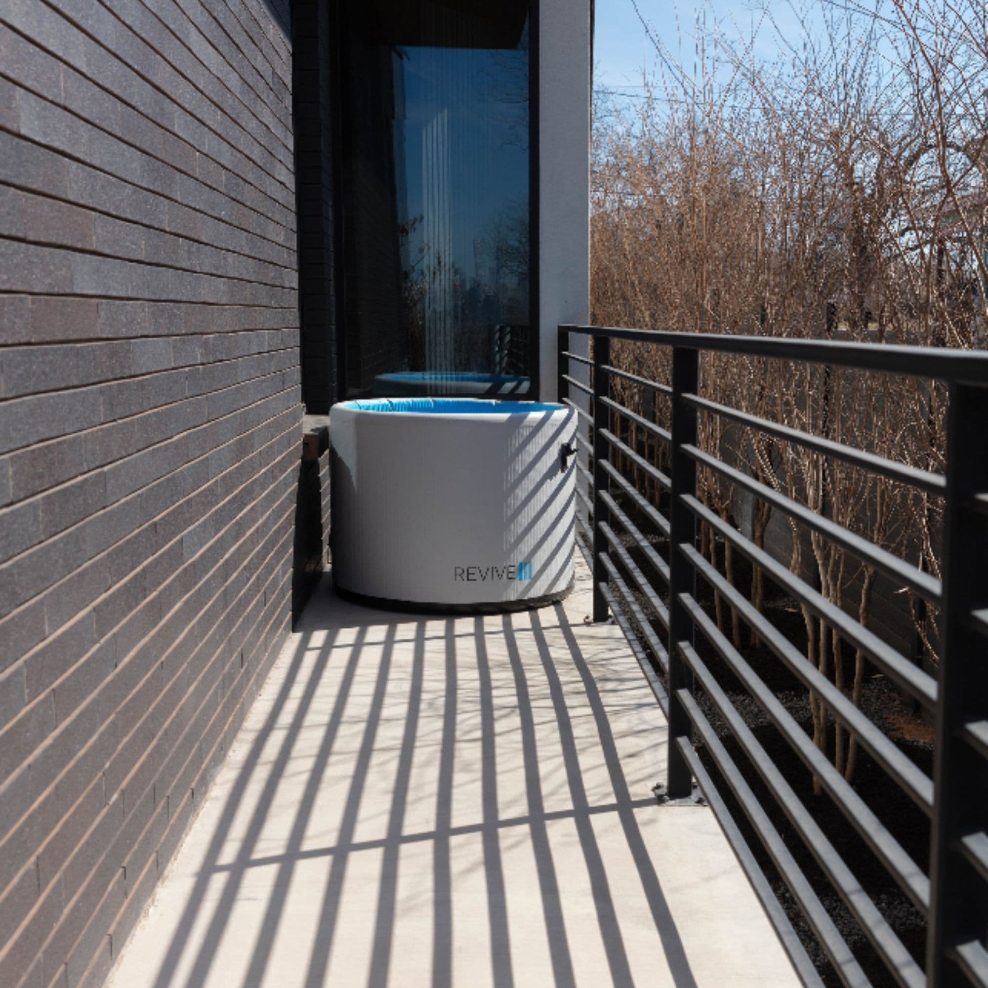 Revive Portable Inflatable Cold Plunge Pod In Balcony Setting With Dried Trees Background