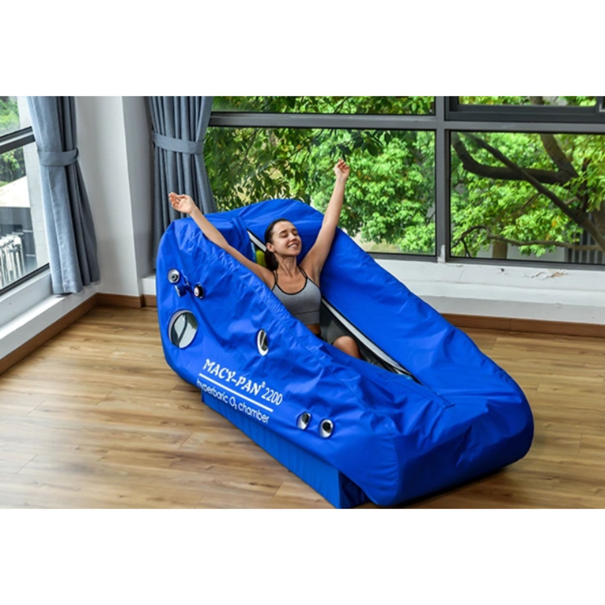 ST2200 Soft Seated Hyperbaric Chamber With A Girl Sitting While Stretching Inside On A Large Glass Window Background