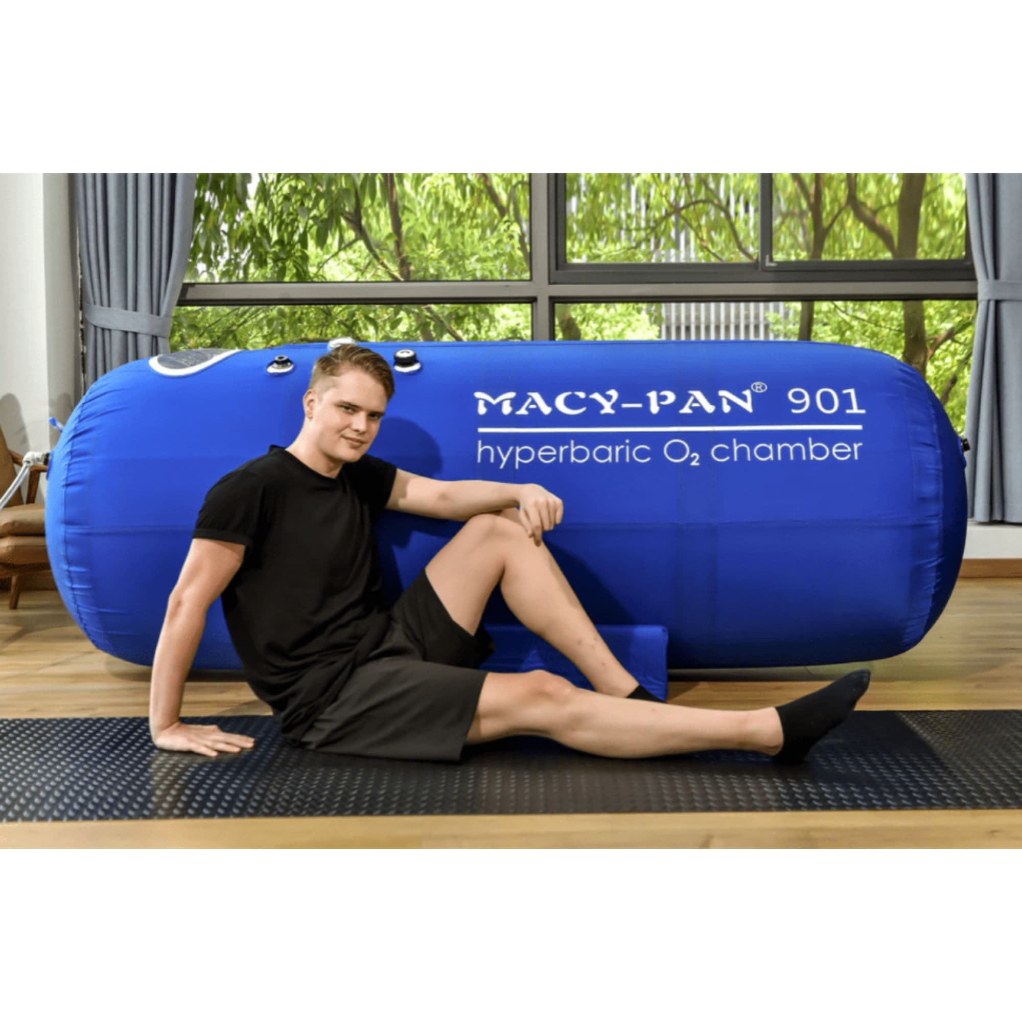 ST901 Portable Lying Hyperbaric Chamber With A Boy Sitting In The Floor By Large Glass Windows With Greenery Views