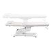 Serenity Electric Treatment Table Side View And Fully Reclined Of White Color Showing An Up And Down Adjustment With Remote Control On White Background