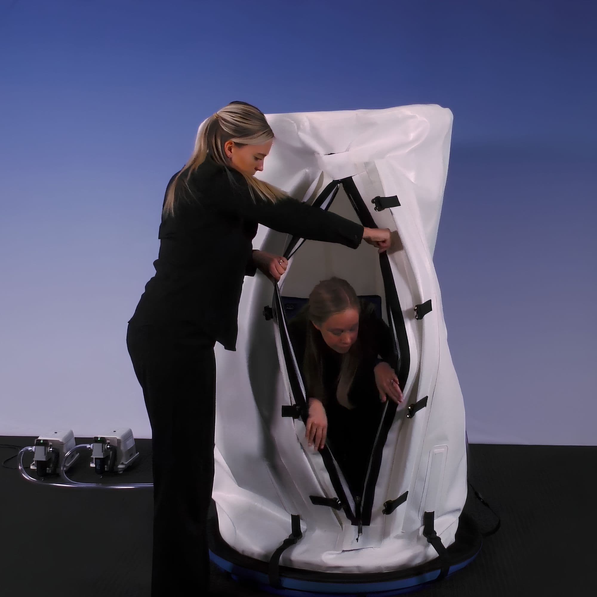 Summit to Sea Dive Vertical 40-Inch Seated Hyperbaric Chamber With Woman Assisting Another Woman Exiting