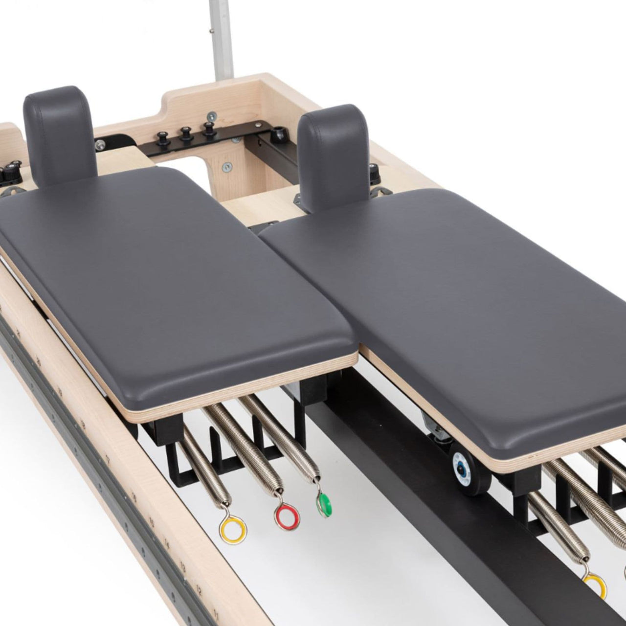 Twin Pilates Reformer Detailed View Showing Split Carriage And Color-coded Spring On White Background