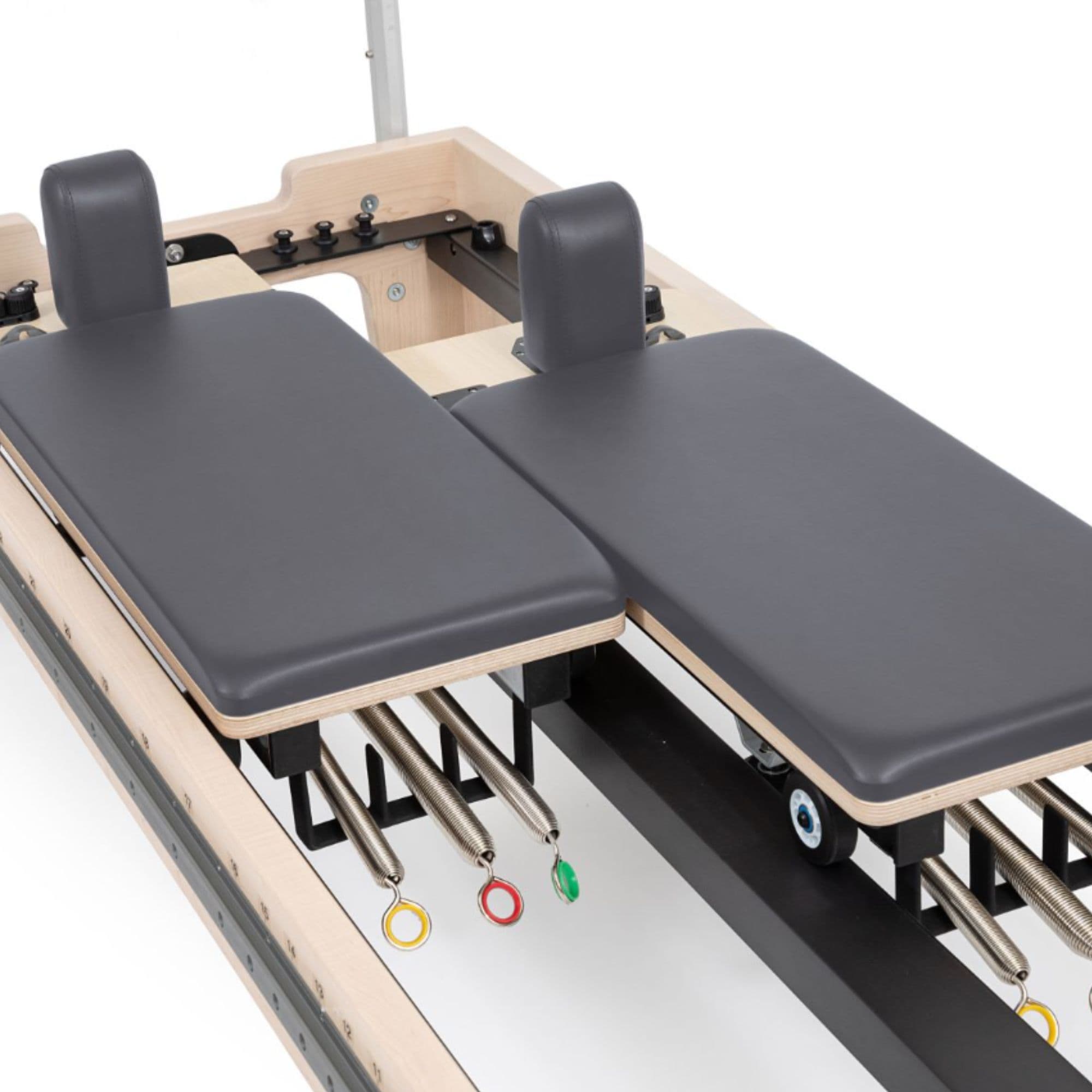 Twin Pilates Reformer Detailed View Showing Split Carriage And Color-coded Spring On White Background
