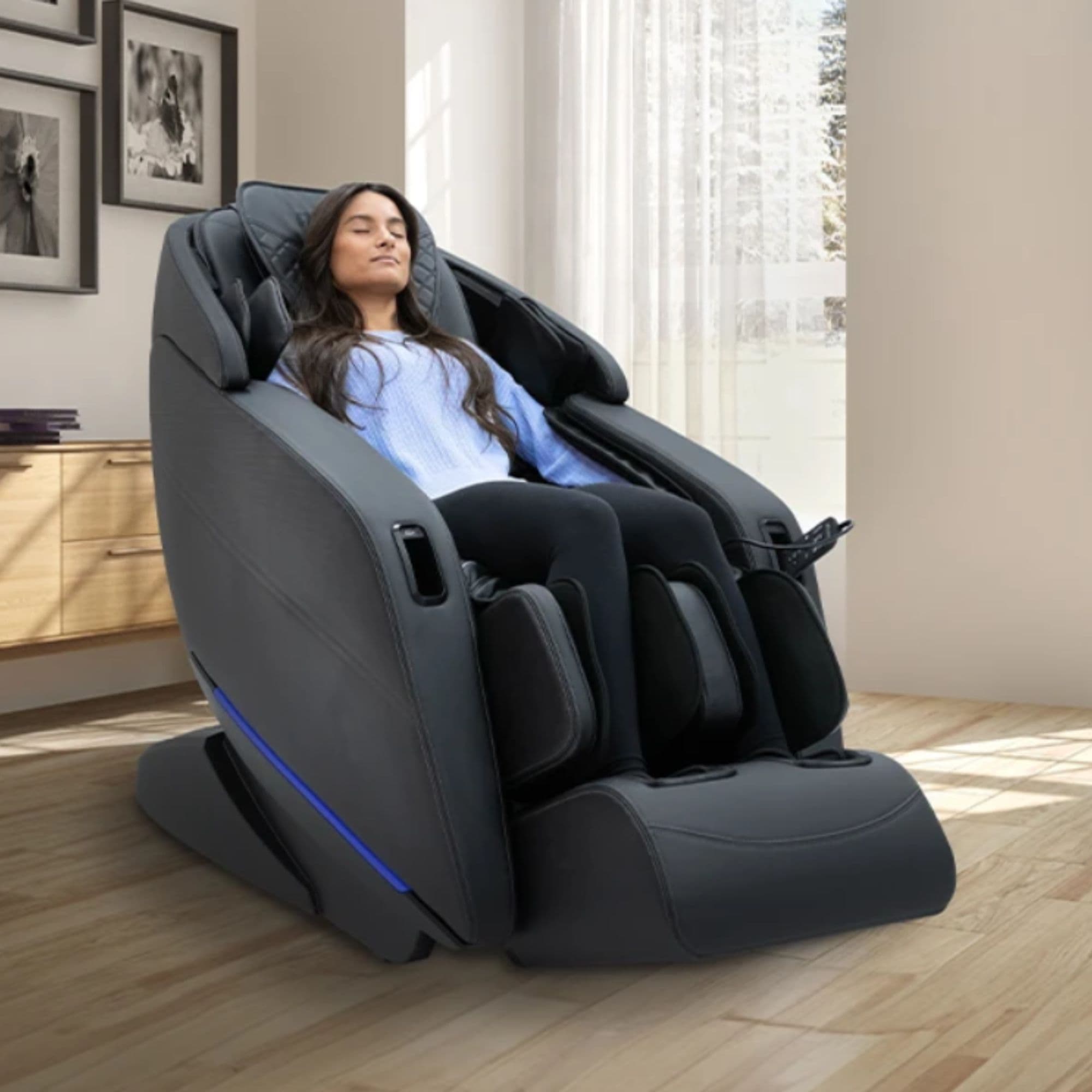 Yugana M780 Massage Chair Black Variant Front Angled View Of A Woman Relaxing Near Large Windows With White Curtains